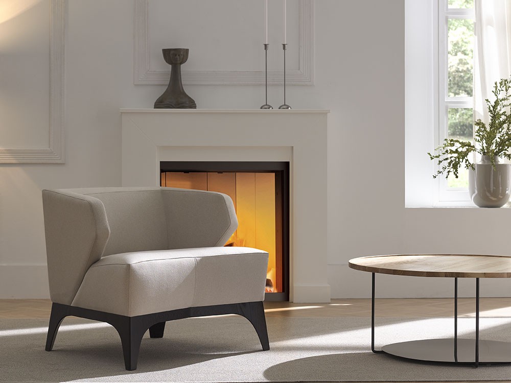 Kida combina formas esenciales y materiales nobles. Su base de madera realza el volumen del asiento con equilibrio y distinción.