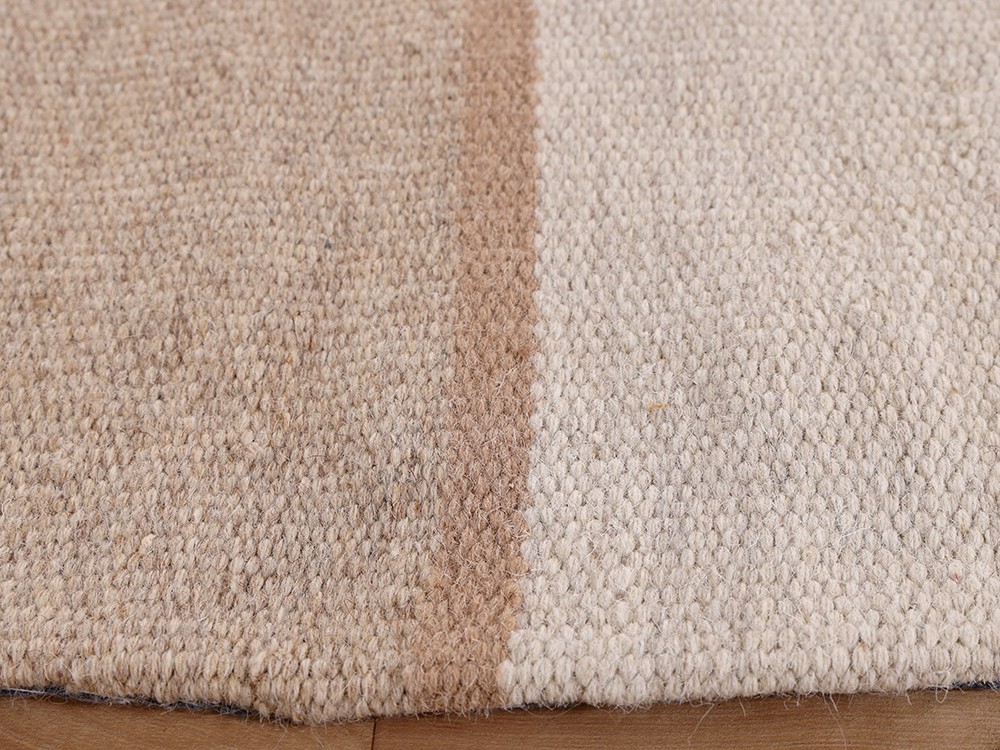 Fabricada en lana tejida a mano color beige y marfil Bay de Unika