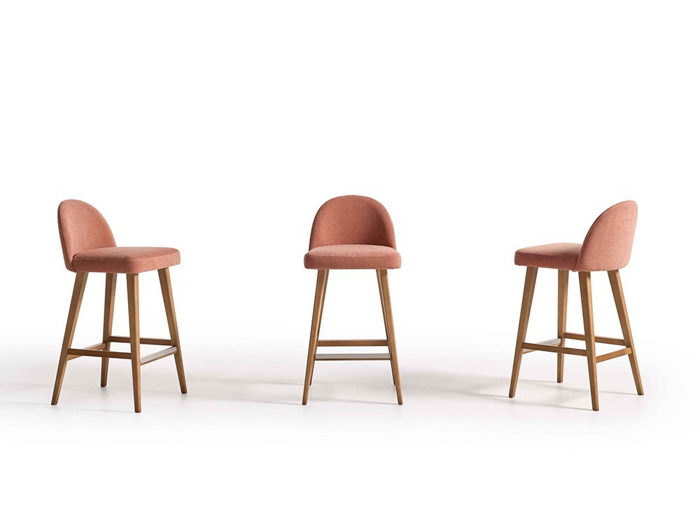 El taburete de diseño 100 de Pérez e Hijos destaca en Seismil Studio, con finas patas de haya y un asiento tapizado suave.